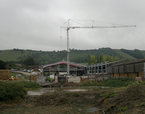 a steel frame building on a building site with a crane above