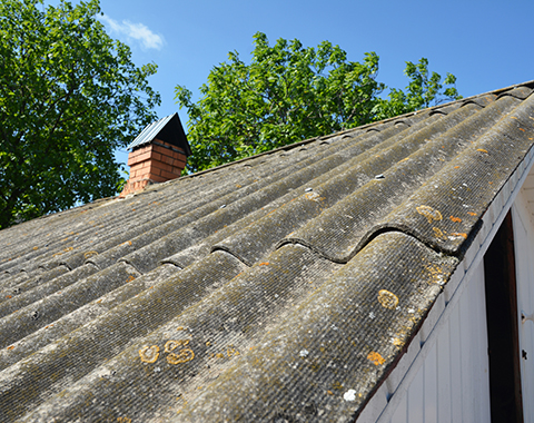 an asbestos roof on an old building with a brick chimney