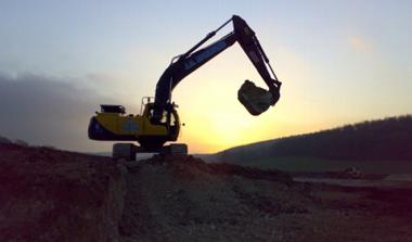 a digger on a mound of rubble at sunset