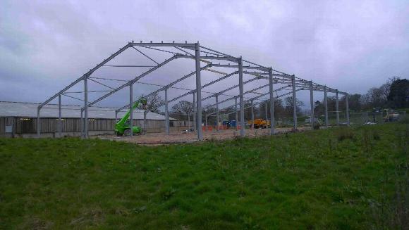 a steel framed structure being built on a grassy land